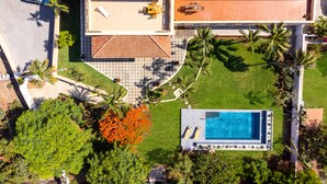 Vista aérea de una propiedad con piscina, patio y zona de estar cubierta al aire libre.