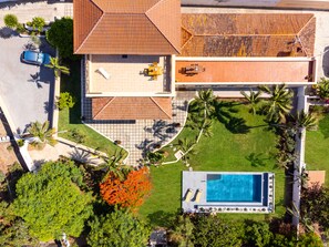 An aerial view of a property with a swimming pool, a patio area, and a covered outdoor seating space.