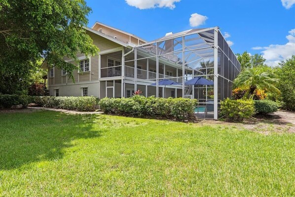 A two-story house with a glass-enclosed porch, a swimming pool, and a well-maintained lawn.