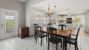 A spacious kitchen with white cabinets, a central island, and a dining area with a wooden table and chairs. - Gorgeous Fairway Facing Estate with Pool in the Dunes Golf and Country Club (Sanibel)