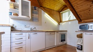 Eine Küche mit weißen Schränken, einem Geschirrspüler, einem Backofen, einer Mikrowelle und einem Fenster mit Jalousien.