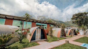 A building with multiple dome-shaped structures, a pathway, and surrounding greenery. - Refugio Suncamal By Rotamundos (Cumanda)
