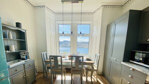 Una cocina con una mesa de comedor, sillas y vistas al exterior.