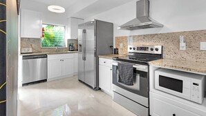 Een moderne keuken met roestvrijstalen apparatuur, witte kasten en een granieten aanrecht.