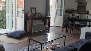 A modern living room with a glass coffee table, a sofa, and a dining area with a kitchen in the background. - 2 beds 4 pers. 1,5km from Palais /swimming pool/parking 12min walk center Cannes (Cannes)
