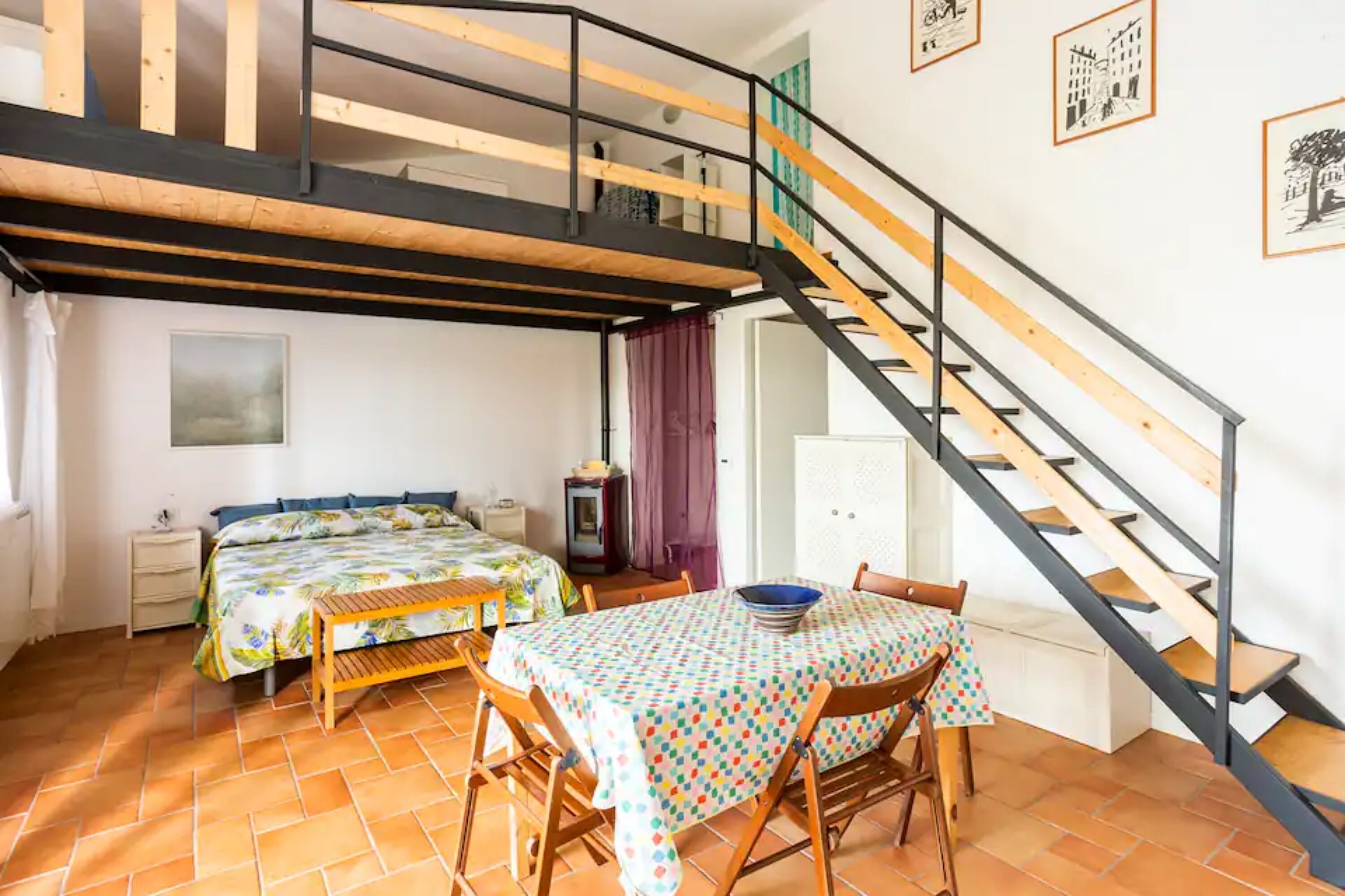 Une chambre avec un lit en mezzanine, une table à manger avec des chaises et un escalier.