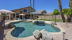 A backyard with a swimming pool, lounge chairs, umbrellas, and a house. - Moore House ~ Downtown Gilbert w/ Pool & Yard Games (Gilbert)
