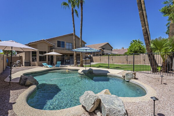 A backyard with a swimming pool, lounge chairs, umbrellas, and a house. - Moore House ~ Downtown Gilbert w/ Pool & Yard Games (Gilbert)