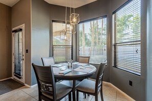 A dining area with a round table, six chairs, and a chandelier. - Moore House ~ Downtown Gilbert w/ Pool & Yard Games (Gilbert)