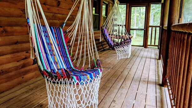 Una cabaña de madera con dos columpios de macramé colgados del techo.