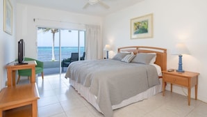 Ein Schlafzimmer mit Bett, Nachttisch, Sessel, Schreibtisch und Meerblick.