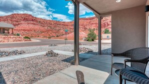 Un portico coperto con posti a sedere all'aperto, vista su formazioni rocciose rosse e cielo sereno.