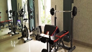 Un gimnasio con diversos equipos de ejercicio, como una prensa de banca, una máquina de remo y una bicicleta estática.