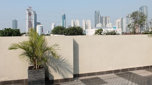 Una terraza en la azotea con vistas a un horizonte urbano, incluyendo edificios altos y una palmera.