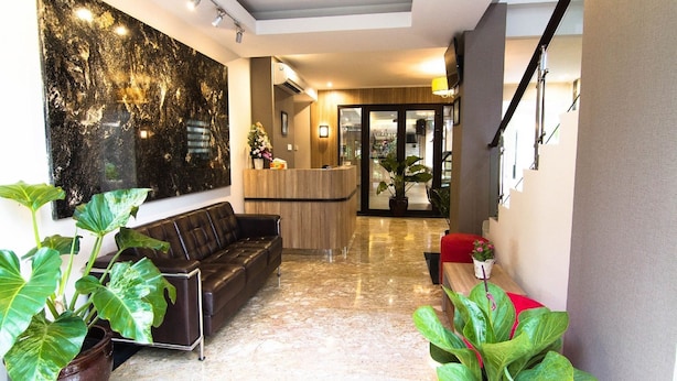 Un vestíbulo moderno con mostrador de recepción, zona de estar y plantas en macetas.