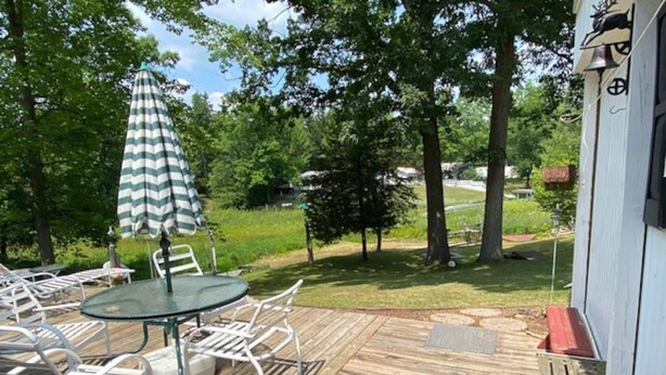 Une terrasse dotée de mobilier d’extérieur, comprenant une table et des chaises, ainsi qu’un parasol à rayures.