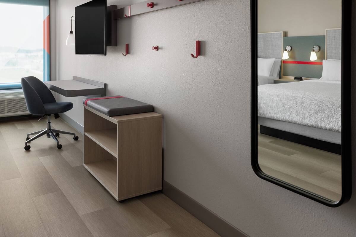 A hotel room with a desk, chair, and a bed.