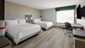 Une chambre d’hôtel avec deux lits, un bureau et une chaise.