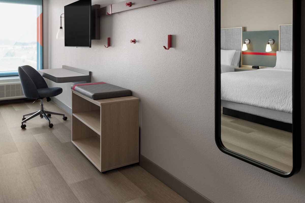 A hotel room with a desk, chair, and a bed.