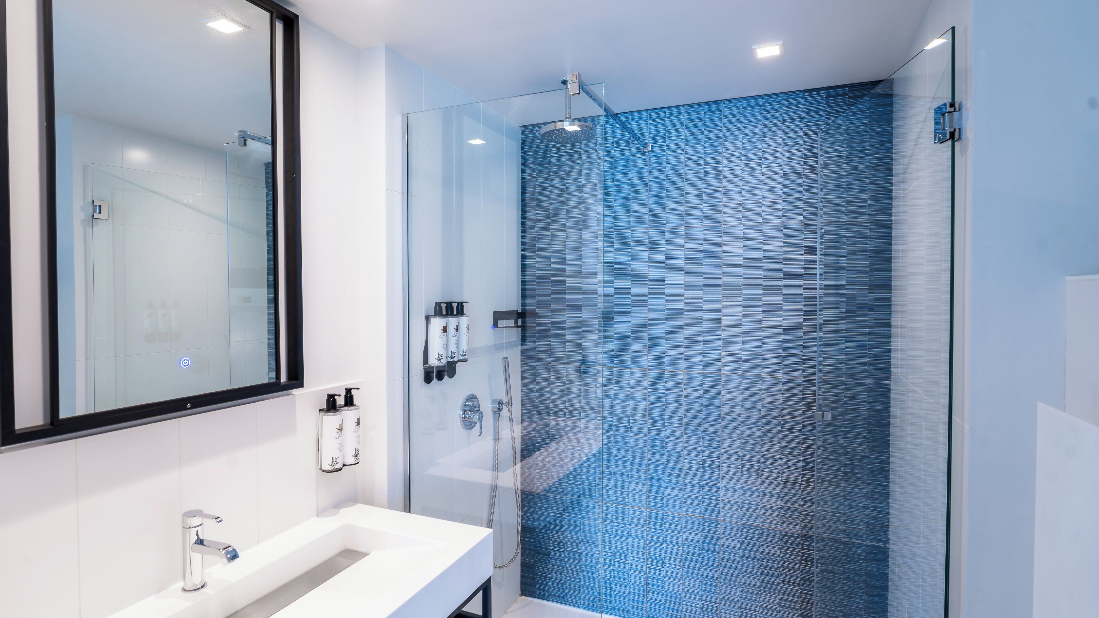 A modern bathroom with a glass shower enclosure, a white sink, and a large mirror.