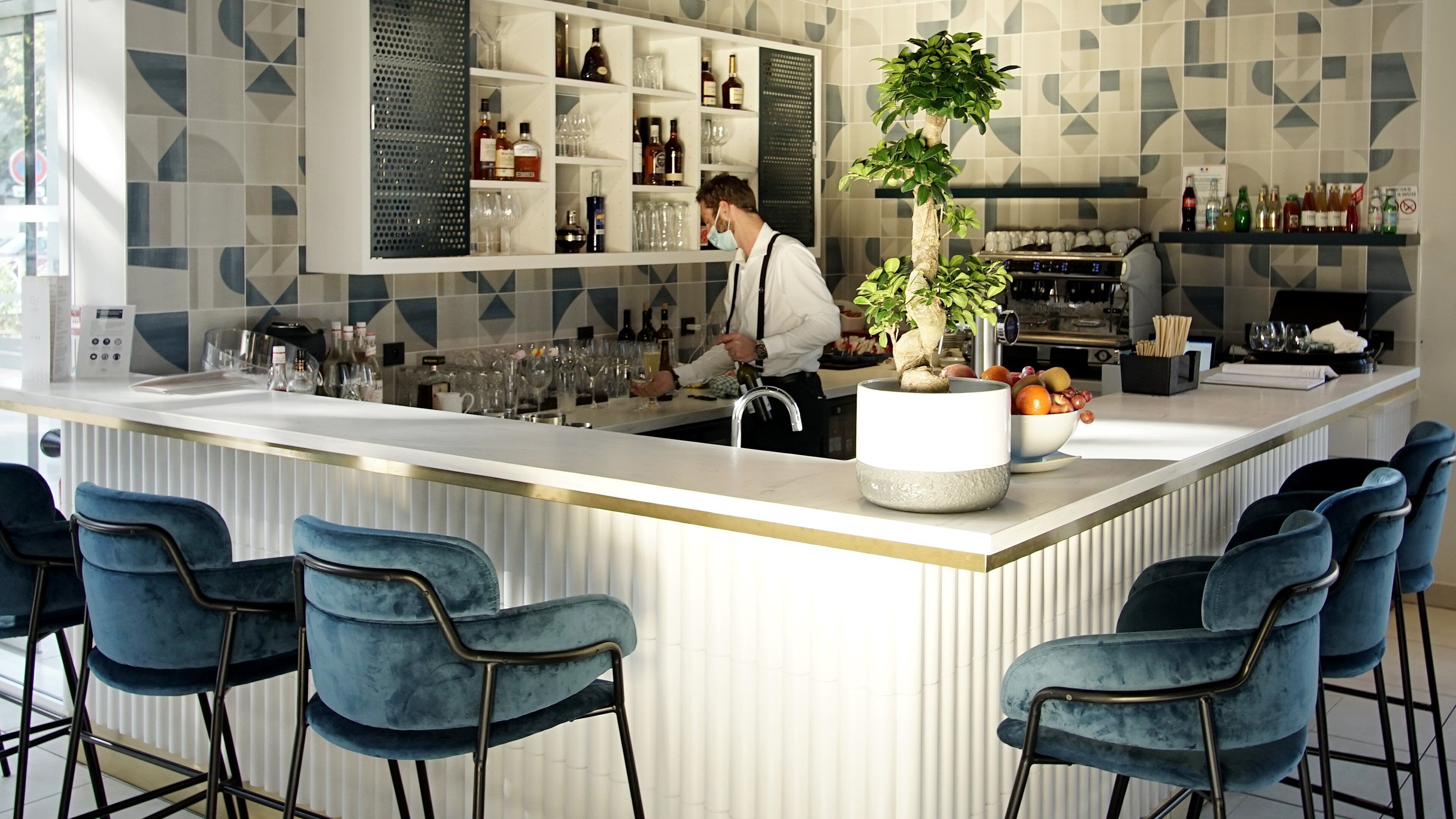 Un espace bar moderne comprenant un comptoir, des sièges et une variété de bouteilles et de verres.