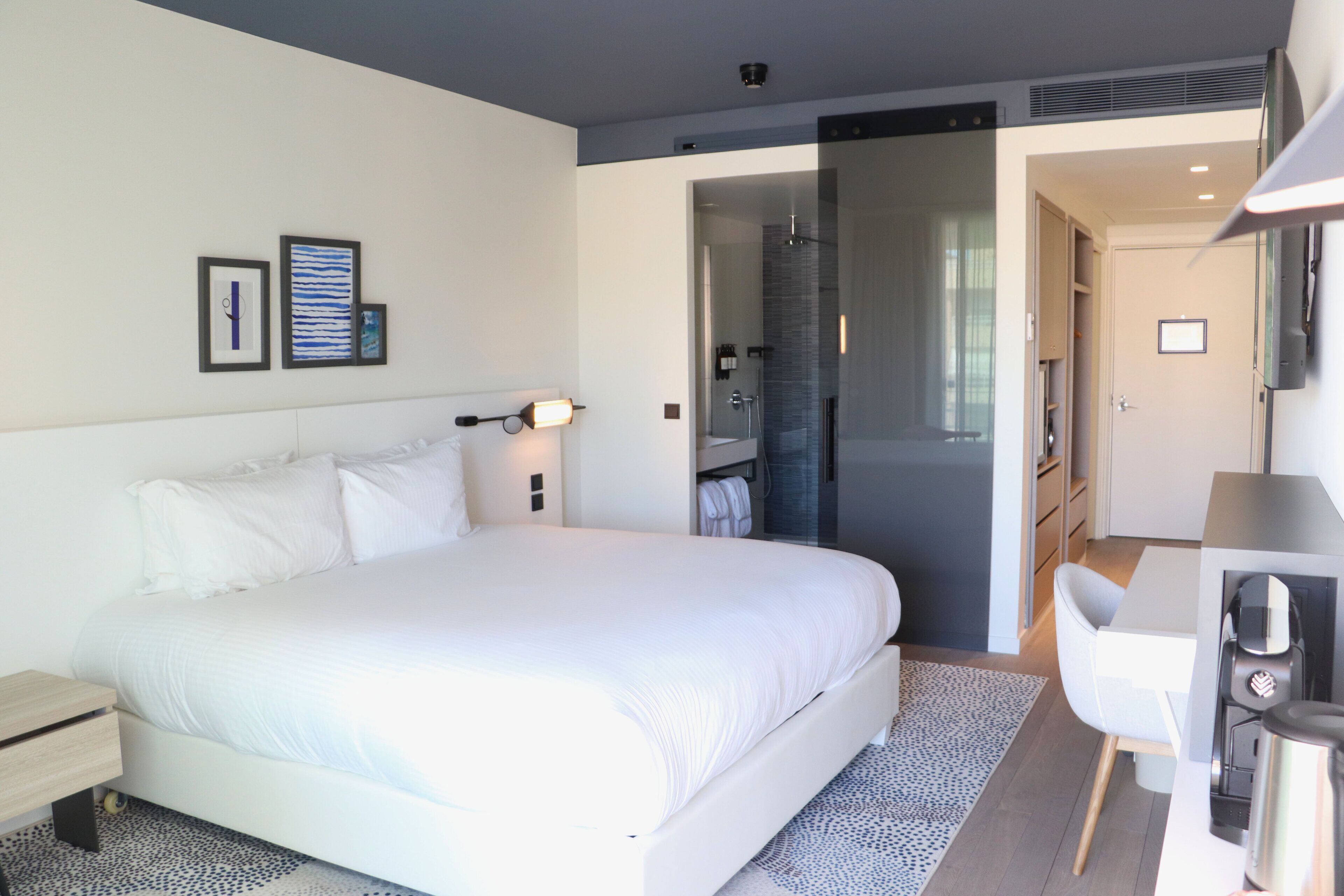 Une chambre d’hôtel moderne avec un grand lit, un bureau et un dressing.
