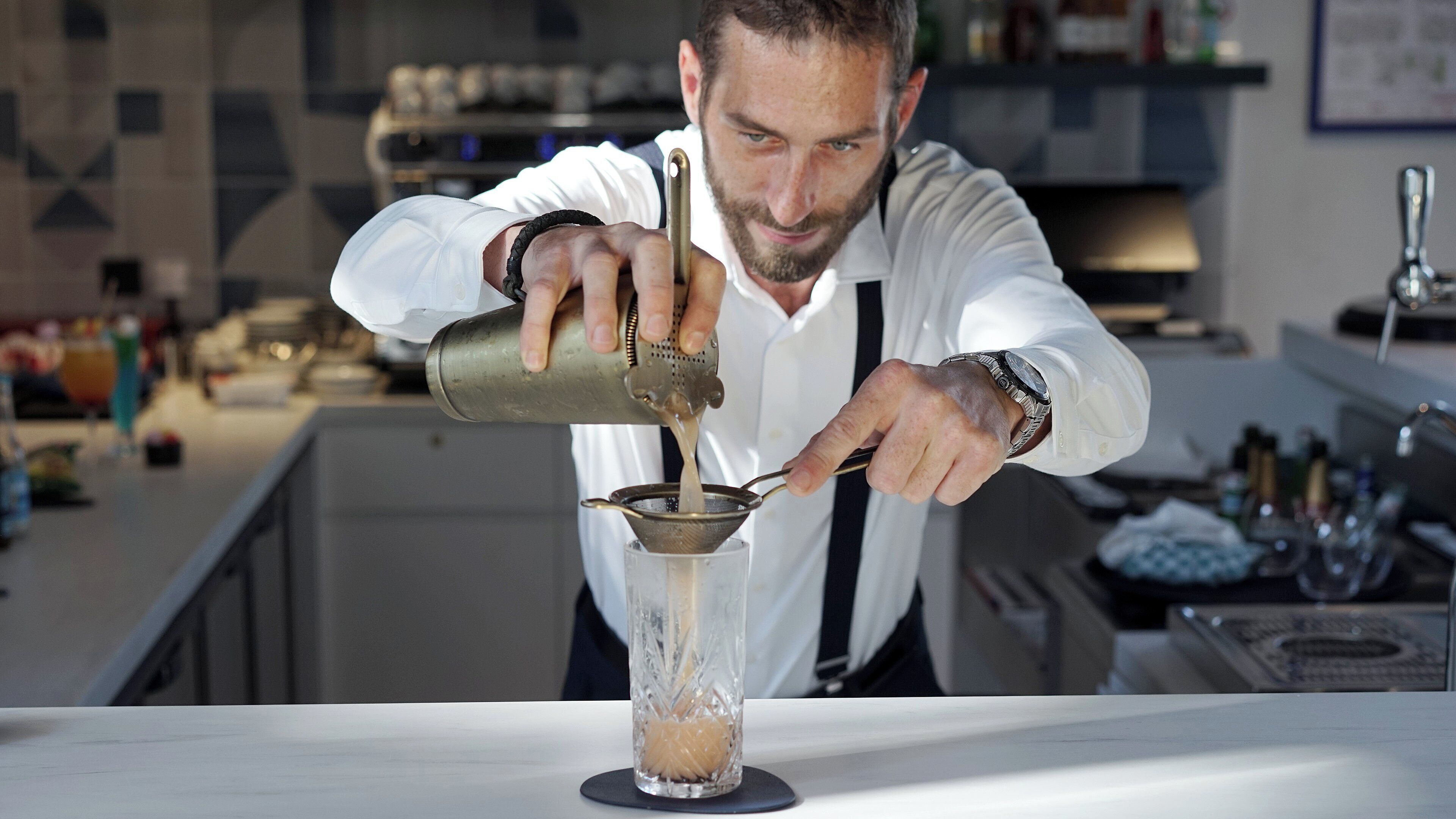 A bartender pouring a drink into a glass.