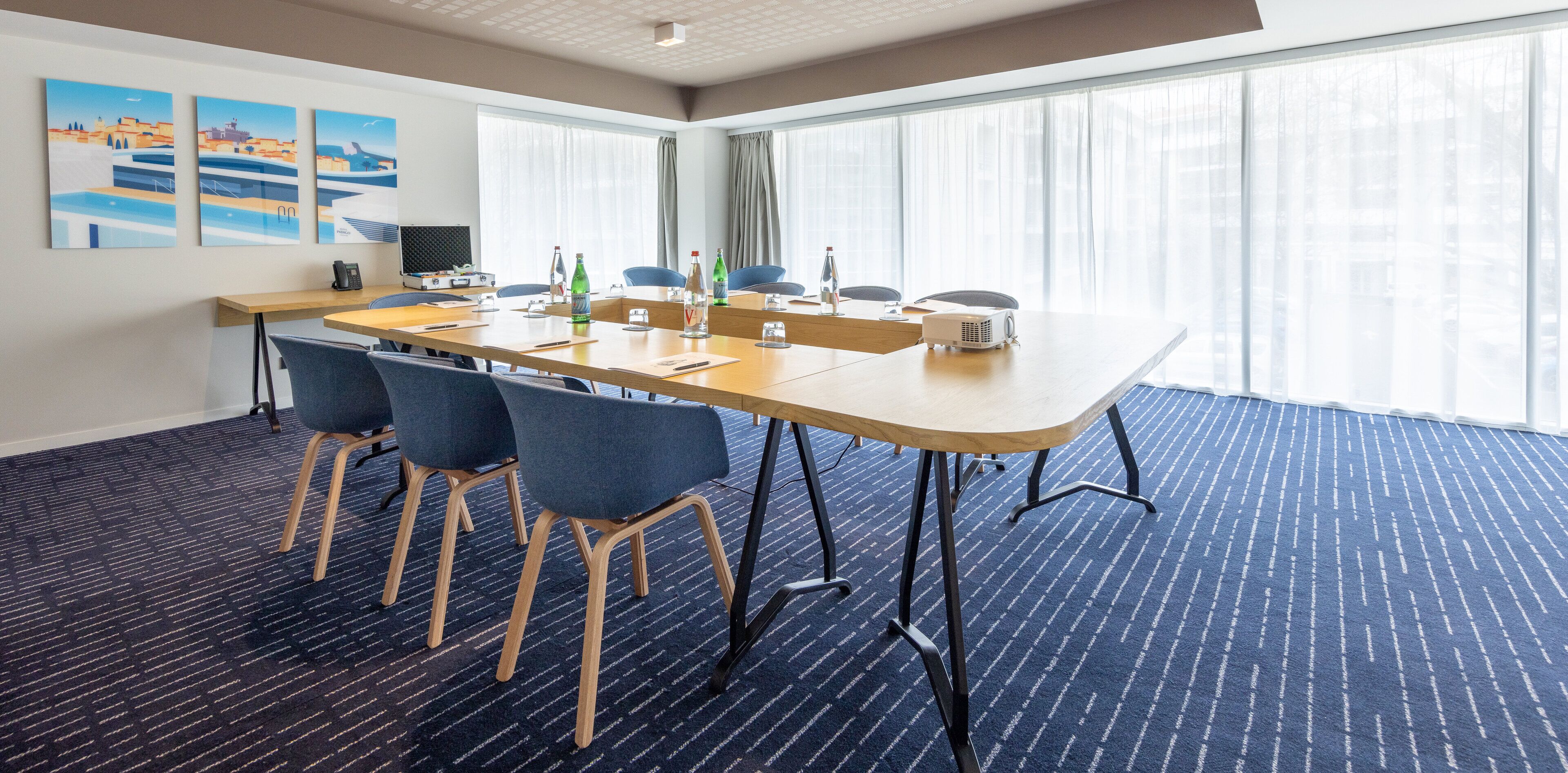 A conference room with a long table, blue chairs, and a projector.