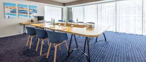 A conference room with a long table, blue chairs, and a projector.