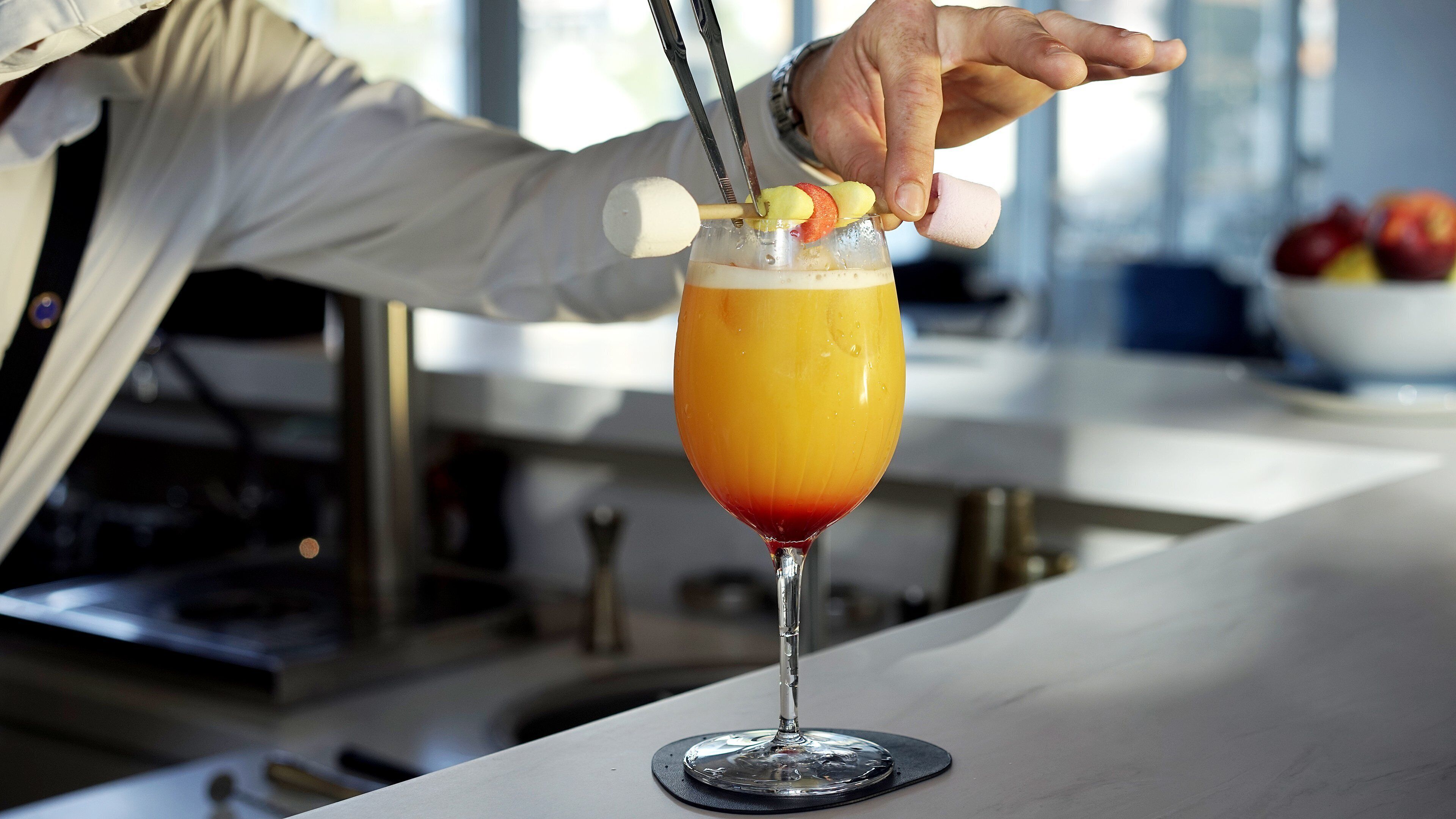 A bartender preparing a cocktail with a fruit garnish.