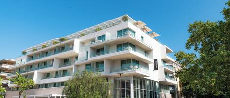 A multi-story hotel with balconies, a glass facade, and outdoor seating.