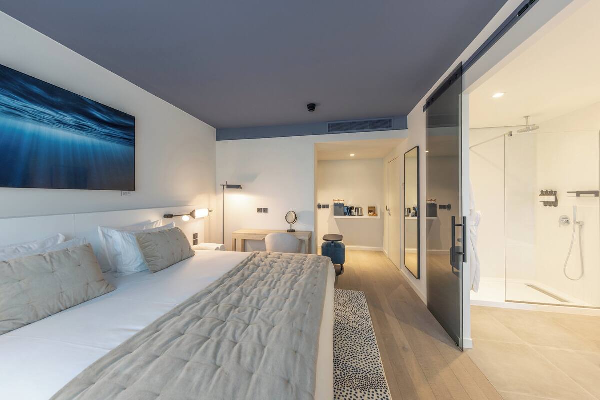 A modern bedroom with a large bed, bedside table, and a walk-in closet.