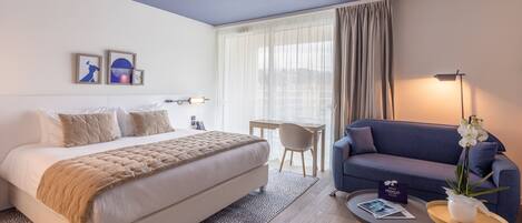 Une chambre d’hôtel avec un lit, un canapé, un bureau et une chaise.