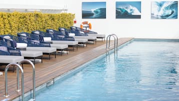 A pool area with lounge chairs, a wooden deck, and wave-themed artwork on the walls.