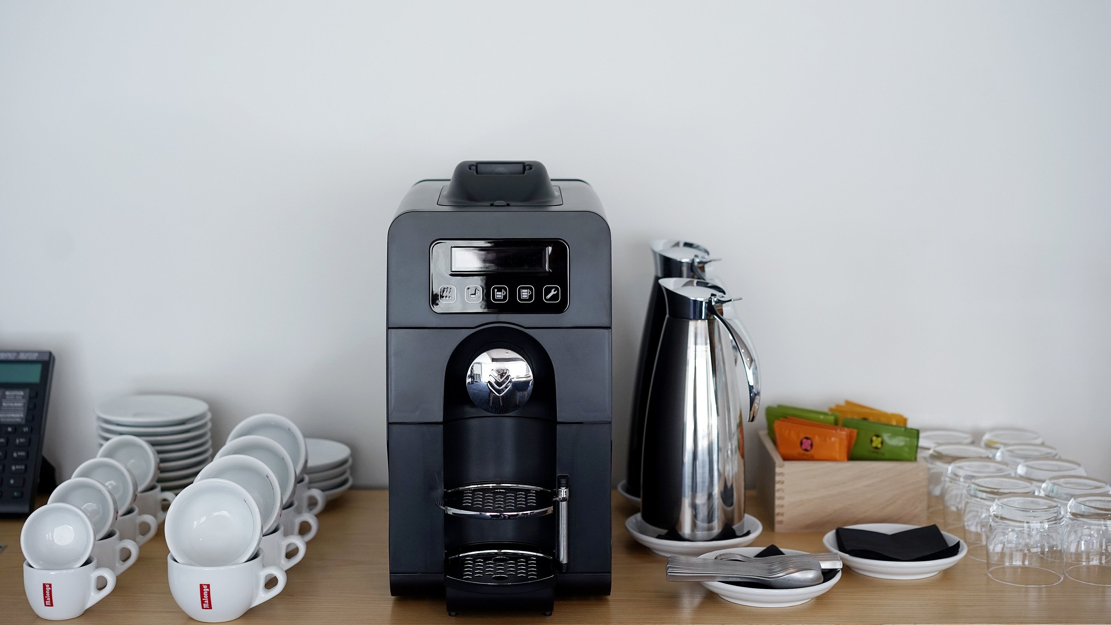 Una máquina de café con pantalla digital, depósito de agua y jarra.