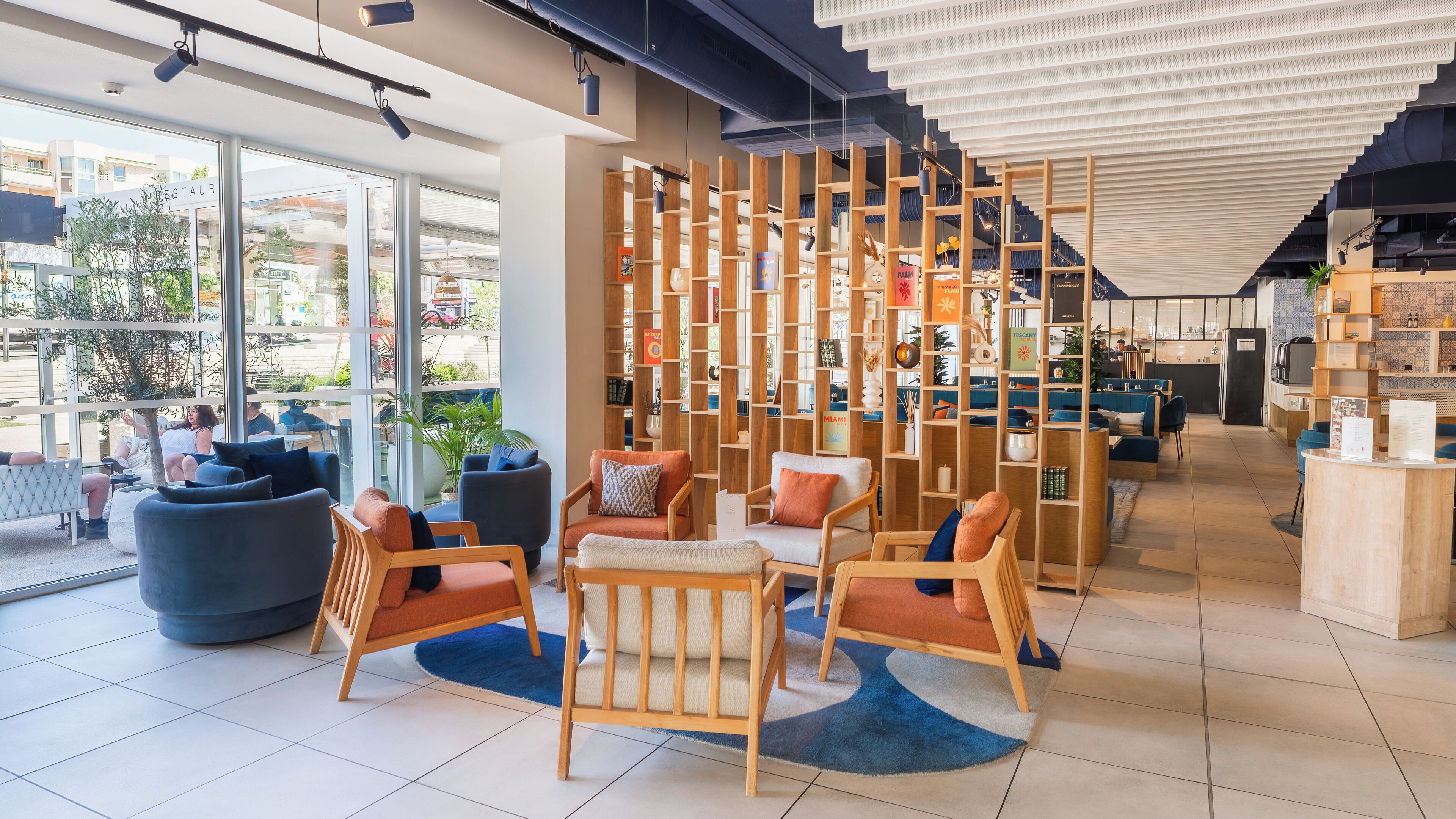 Un intérieur moderne avec des coins salon, une cloison en bois dotée d’étagères et une vue sur l’extérieur.