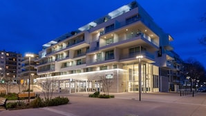 A multi-story hotel with a modern design, featuring balconies, large windows, and a well-lit entrance. - Hotel Indigo Cagnes-sur-Mer by IHG (Cagnes-sur-Mer)