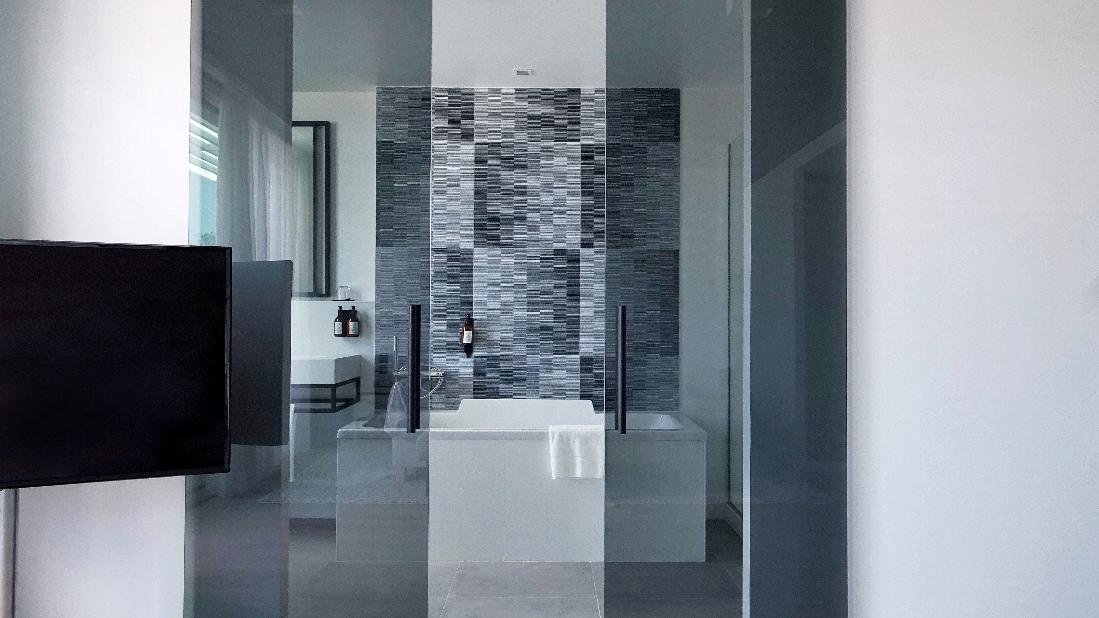 Un bagno moderno con cabina doccia in vetro, un lavandino bianco e uno specchio grande.