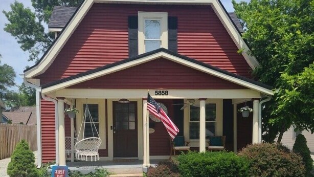 Ein rotes Haus mit Veranda, Briefkasten und einer amerikanischen Flagge.