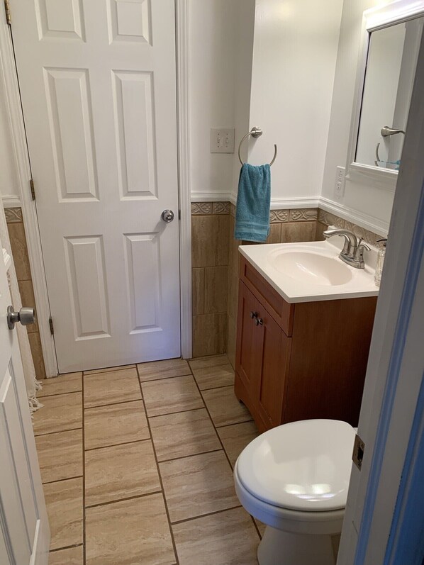 Un baño con inodoro blanco, lavamanos y espejo.