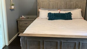 Ein großes Bett mit Holz-Kopfteil, einem Nachttisch und einem Beistelltisch.