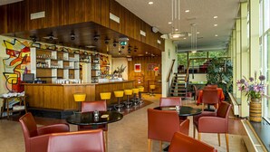 A modern bar area with a wooden counter, bar stools, and a vibrant abstract mural. - Pension Homeland (Amsterdam)