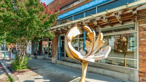 A sculpture in front of a building with large windows and a brick facade. - The Rhododendron - a PMI Scenic City Rental (Chattanooga)