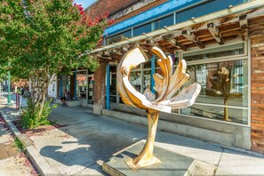 Stunning sculpture adorns the sidewalk outside this building, set against a backdrop of large windows and a charming facade.