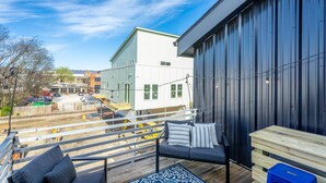 A balcony with a sofa and a table, overlooking a parking area and buildings. - The Rhododendron - a PMI Scenic City Rental (Chattanooga)