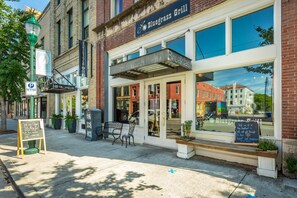 Une devanture de magasin avec une enseigne indiquant « Bluegrass Grill », un panneau de signalisation pour le stationnement et un tableau noir affichant divers messages.