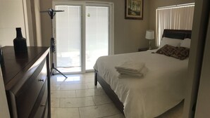 A hotel room with a bed, a nightstand, a lamp, a dresser, and a sliding glass door leading to a balcony. - Luxury Casita at Desert Estate in Scottsdale (Scottsdale)