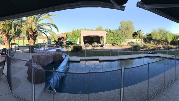 A pool area with a safety fence, lounge chairs, and a covered seating area. - Luxury Casita at Desert Estate in Scottsdale (Scottsdale)