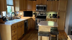 A kitchen with wooden cabinets, a microwave, stove, and a ceiling fan.
