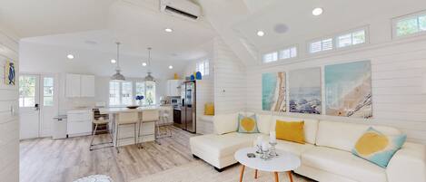 A spacious living area with a white sofa, a coffee table, and a kitchen area with a large island.